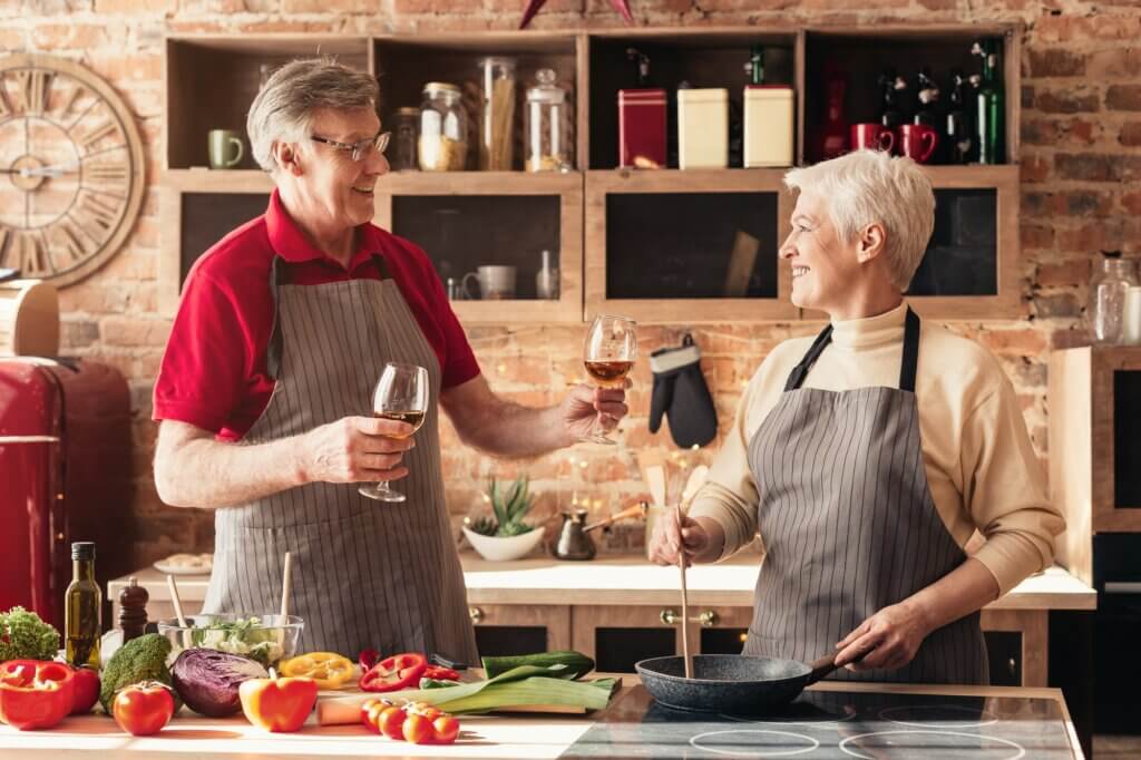 Affectionate retired couple drinking wine in kitchen