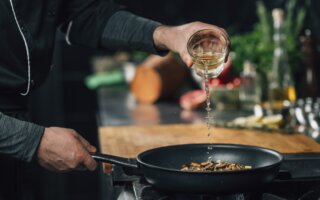 Chef Pouring White Wine into Frying Pan with Sliced Shiitake Mushrooms