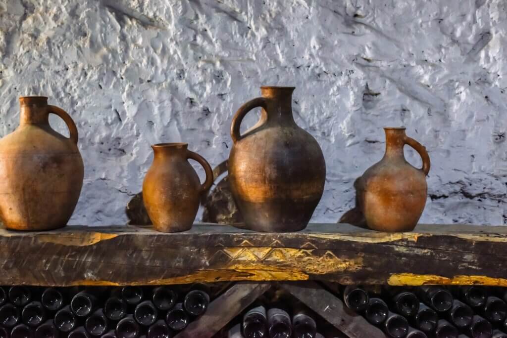 Various old jugs, winemaker's dishes on a wooden shelf in the cellar