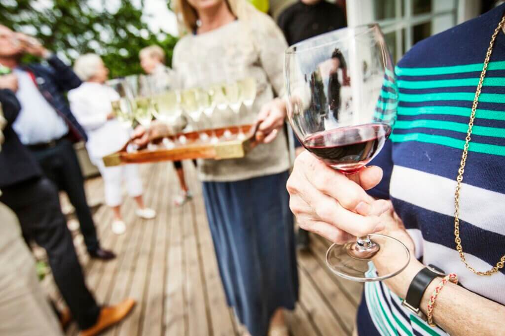 Woman holding glass of red wine at garden party