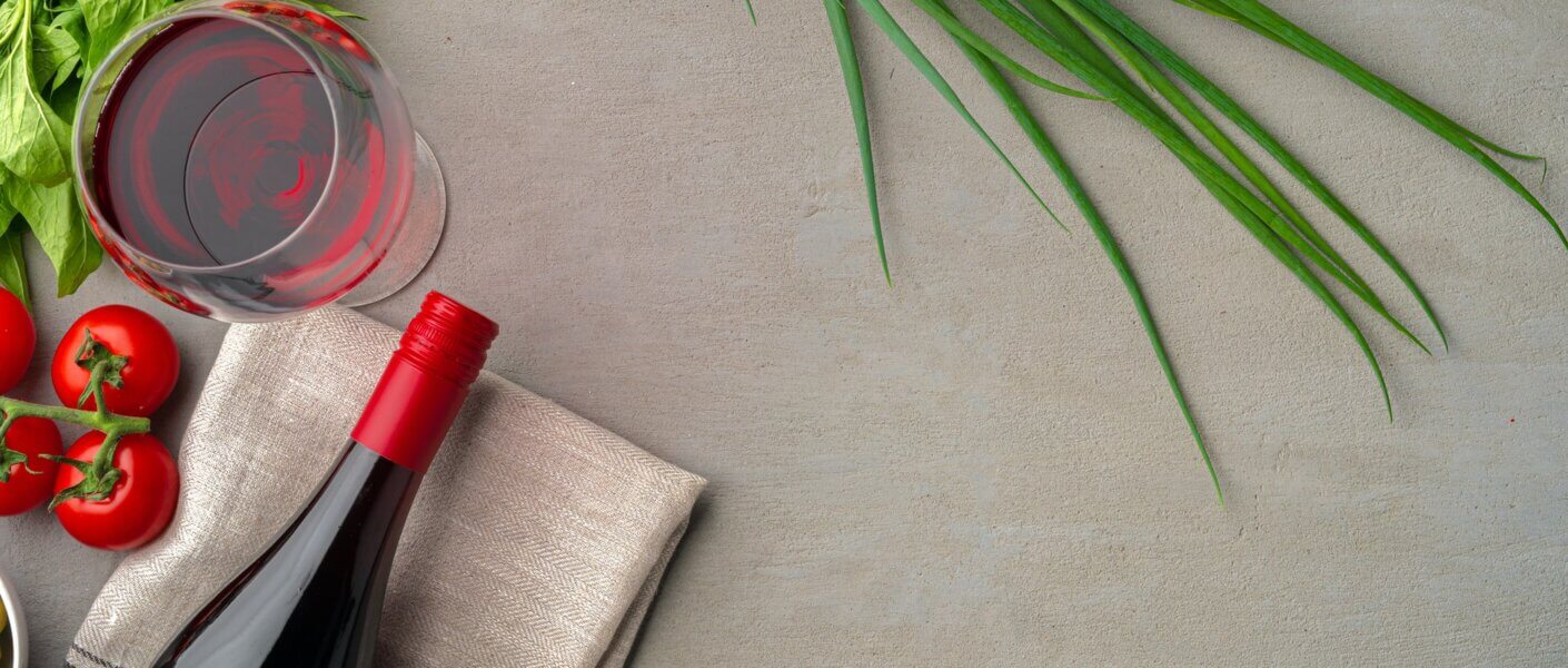 Bottle of red wine on gray surface with vegetables