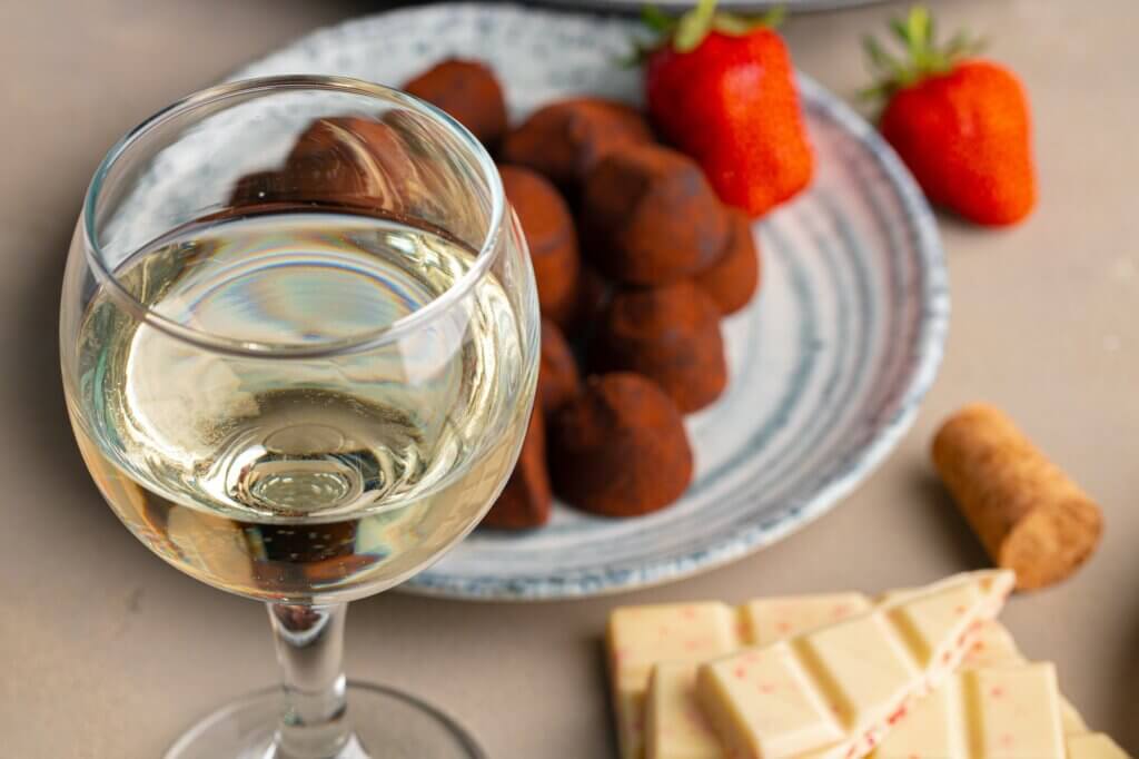 Glass of white wine, truffel chocolates and strawberry close up