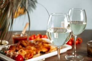 Glass of white wine and homemade food chicken tabaka with vegetables