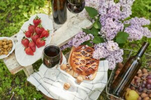 Summer picnic in garden. Wine, pie, fruits and flowers. Still life. Easter lunch and table